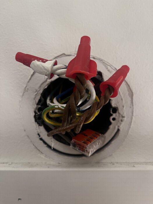 Elcentral med synliga trådar anslutna med röd-vita kabelkopplingar, trådar kommer uppifrån och snett uppifrån in i dosan.