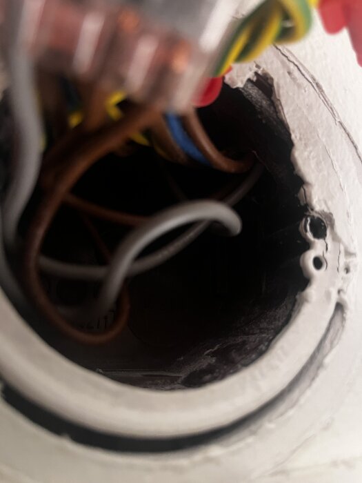 Elcentral med flera färgade kablar synliga inuti en dosa.