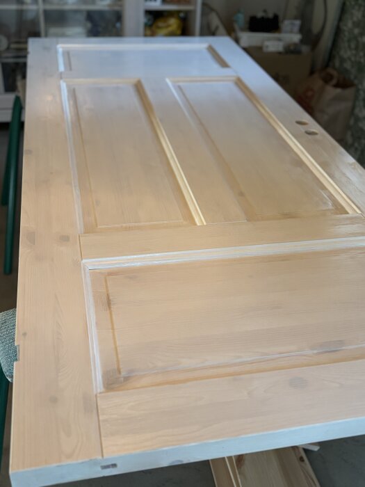 Målad trädörr under renovering, står på ett bord i ett garage eller verkstad.