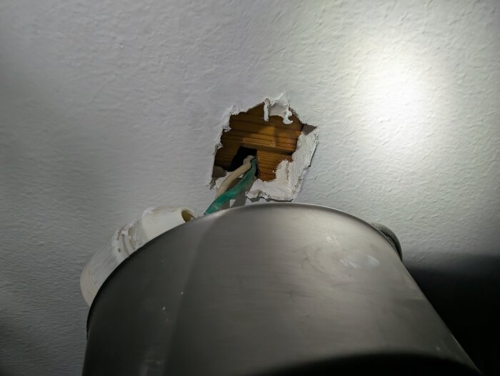Hål i tak med utskjutande elsladdar och en del av en armatur synlig.