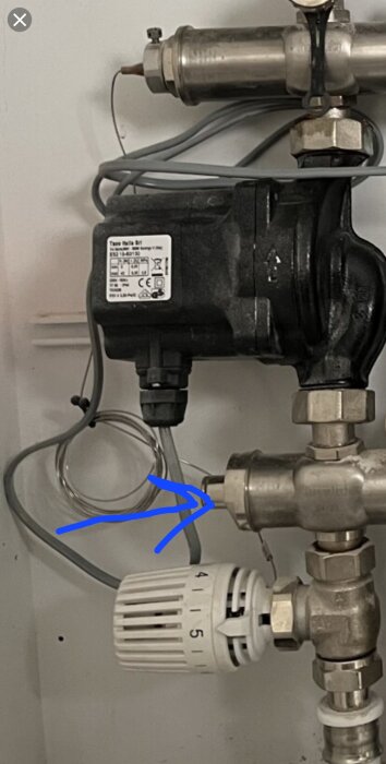 Cirkulationspump för golvvärme med en blå pil som pekar på blandningsventilen.