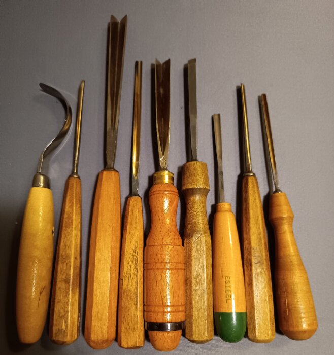 Ett knippe bildhuggarjärn med träskaft, huvudsakligen från Sheffield, placerade på en yta.