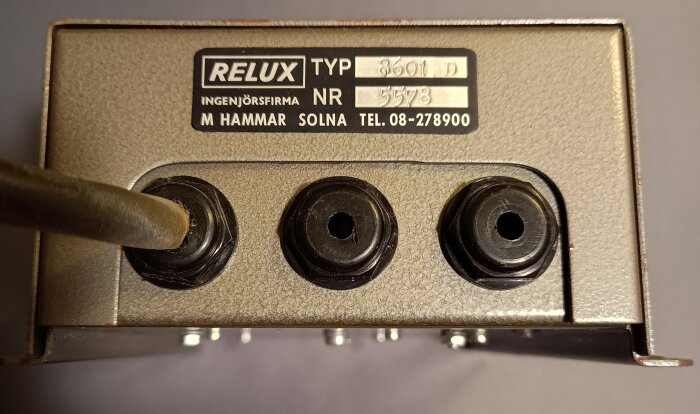 Äldre nätaggregat från ingenjörsfirma Relux, typ 8601 D, med tre svarta kontakter och etikett från Solna.