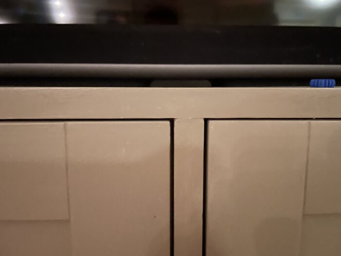 IKEA-skåp modifierat med MDF-paneler, fasade kanter, och tryckknappar istället för standardknoppar. Golvsockeln målad i samma färg.