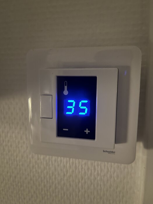 Termostat från Schneider med blå digital display som visar 35 grader.