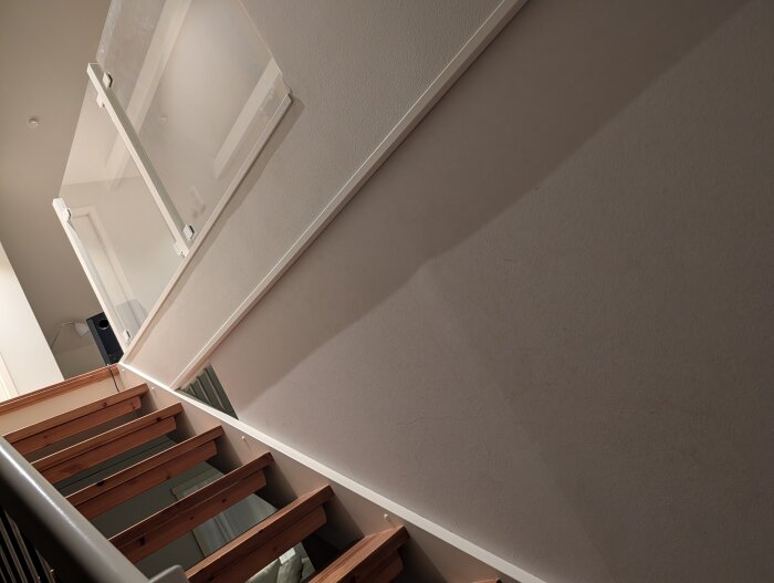 Trappa med trästeg och glasräcke. Detalj syns på de två metallstolpar som nämns för montering av handledare i glasräcket.