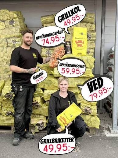 Två personer vid en hög med säckar märkta med olika grillprodukter och priser, som grillkol, tändare och ved.