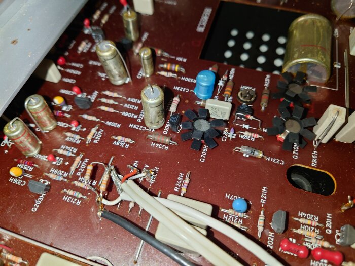 Närbild av kretskort med komponenter och ledningar i en gammal vinylspelare, möjligtvis med tecken på tidigare överhettning.