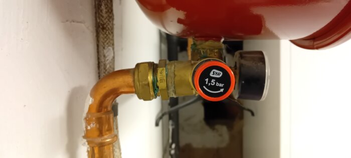 Närbild av säkerhetsventil på expansionskärl, inställd på 1,5 bar. Ventilen är kopplad till en kopparrörledning i ett värmesystem.