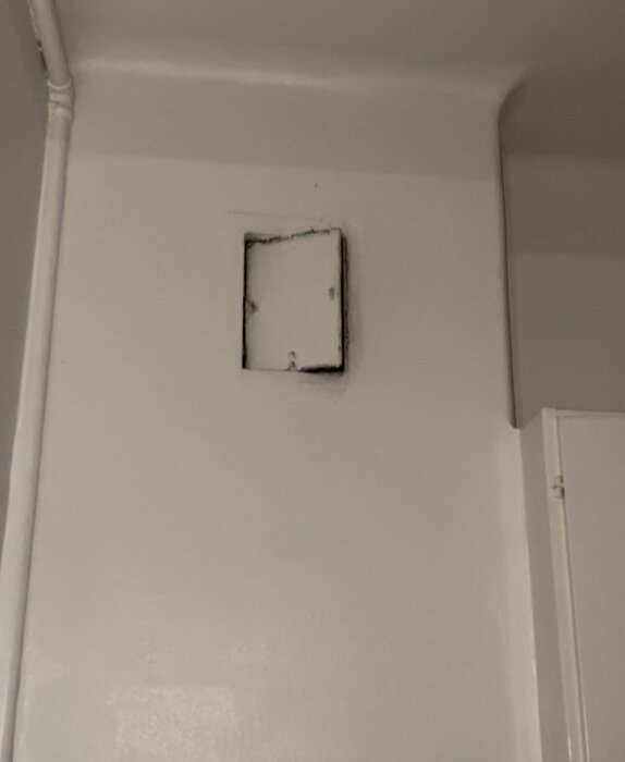 Ventilationskanal ovanför en spis i ett kök, inramad i väggen med lite synliga lämningar av slitage eller smuts runt om kanalen.