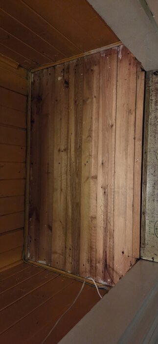 Träplankor på golvet i en garderob, där gammalt plastgolv har tagits bort.