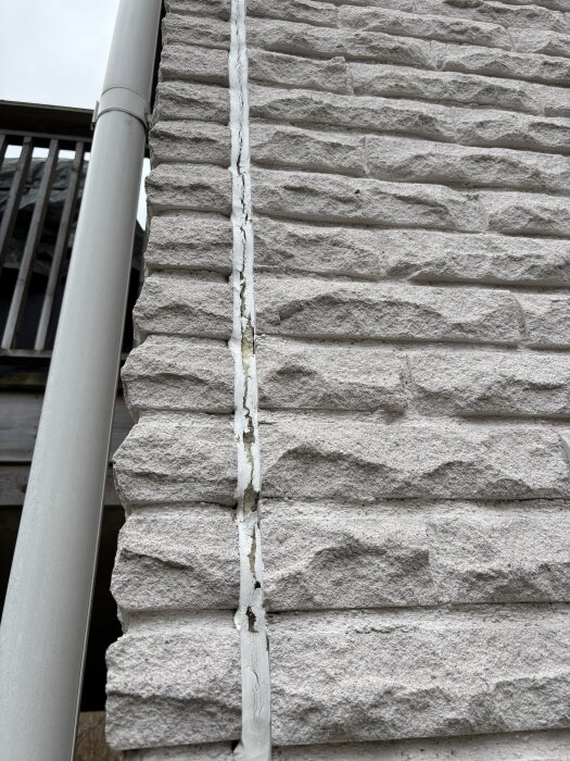 Fog på mexitegelfasad från 80-tal, delvis nedslitet och öppet, vid ett trähus från 40-tal. Diskuteras om tillägg behövs för att täcka glipan.