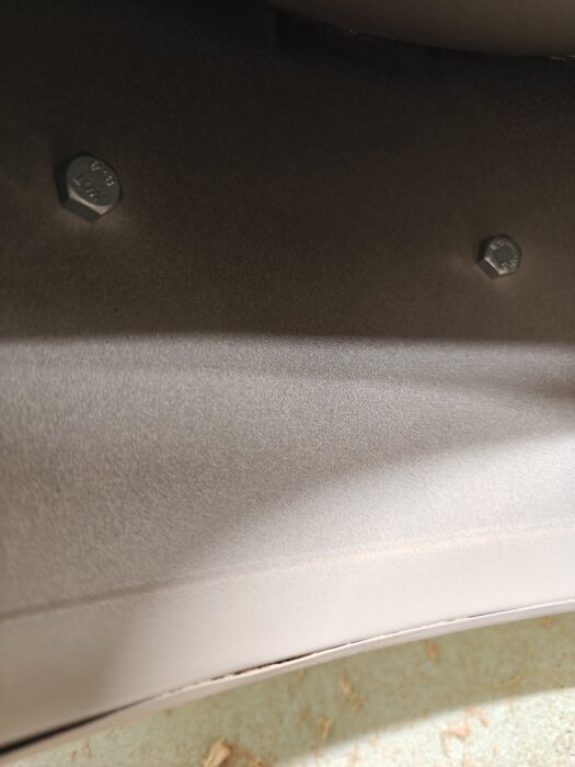 Närbild på två bultar på insidan av en spånsug där handtaget saknas, vilket orsakat läckage av spån.