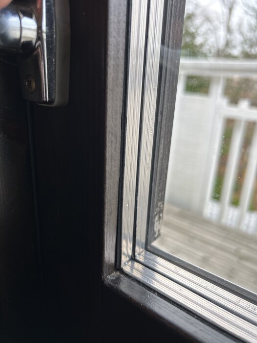 Närbild på ett fönster där en tunn gummilist sitter mellan glaset och fönsterbågen, med fokus på listen.