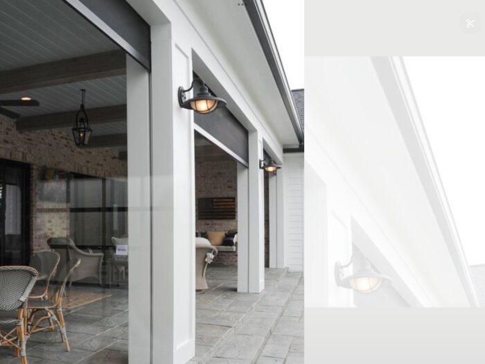 Överbyggd terrass med stolpar och belysning, möblerad med stolar och bord.