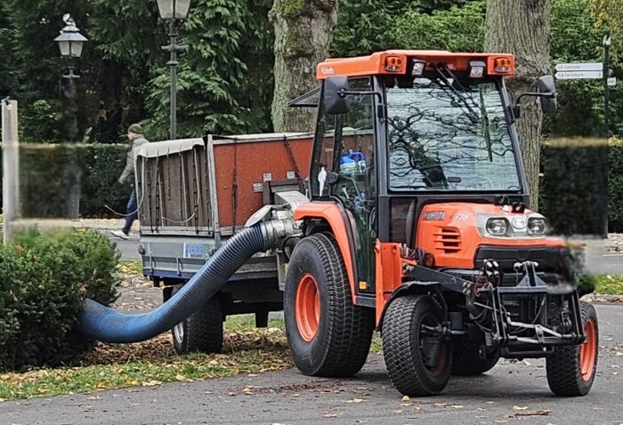 Lövsug med kärra från Kubota i arbete på en gata, slang suger löv från marken.
