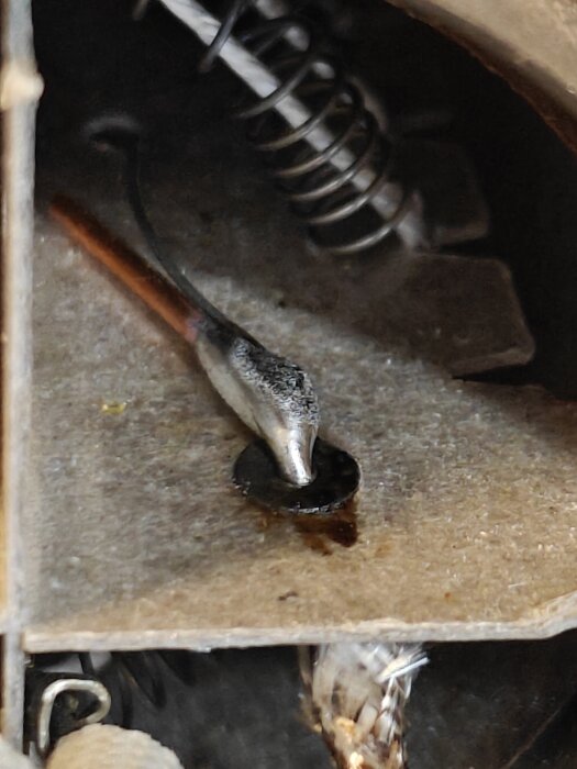 Närbild av en lödning och skarvning inuti en trasig varmluftspistol, med metallfjäder och kablar i bakgrunden.