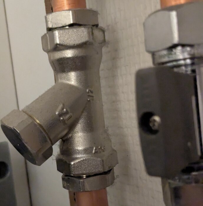 Radiatorledning med Y-formad ventil, antagligen en strypventil. Ventilen är kopplad till kopparrör och verkar justeras med insexnyckel.