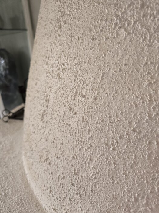 Ojämn putsad yta i närbild, tidigare målad med kalkfärg.