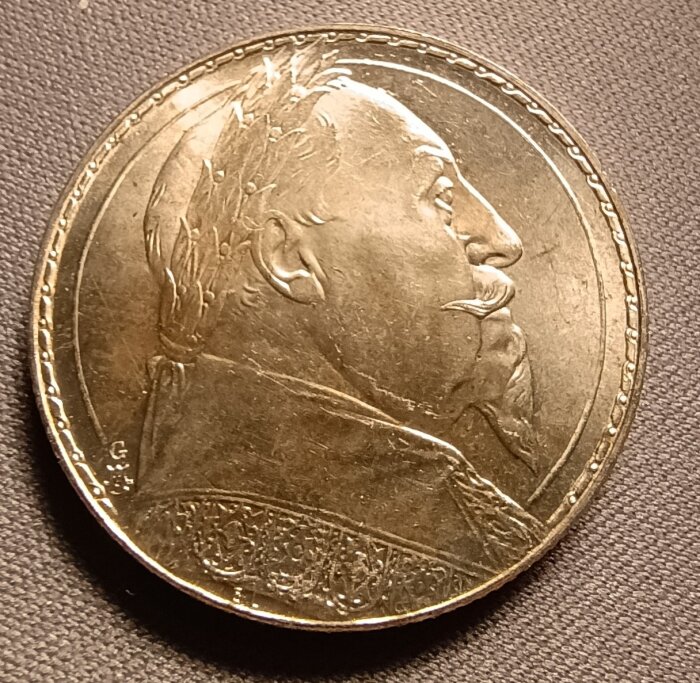 Mynt med en profilbild av Gustav II Adolf, präglad med detaljer och inskriptioner, fotograferad mot en texturerad yta.