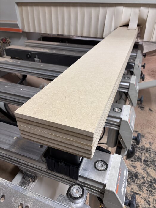 Träplankor av sju lager tricoya i en fräs, redo för bearbetning av svängda socklar med "shadow gap".