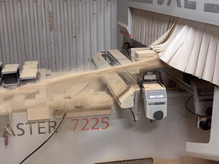 Träbearbetningsmaskin genererar sågspån medan den fräser material i ett dammigt arbetsutrymme.