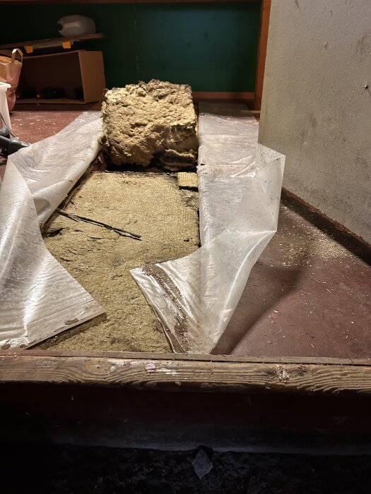 Upplyft golv med synlig isolering och plastfolie, pågående renovering.