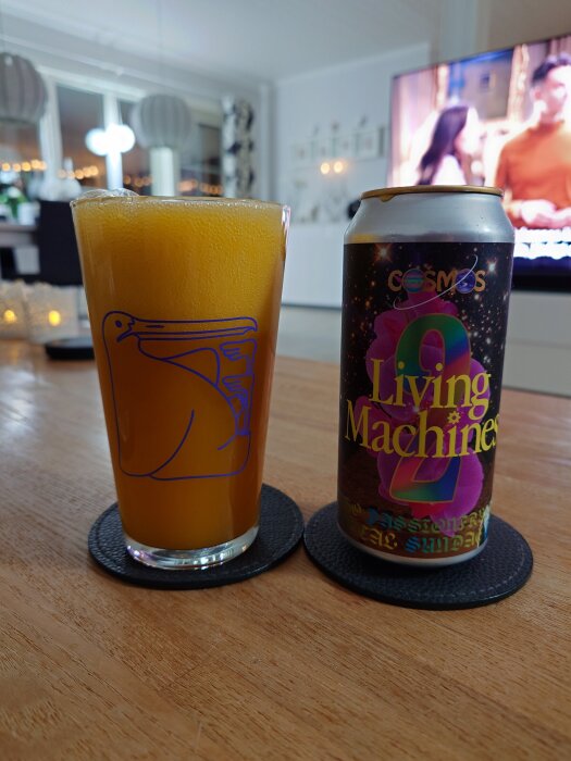 Glas med gul dryck och en burk märkt "Living Machine" står på ett bord, med en TV i bakgrunden.