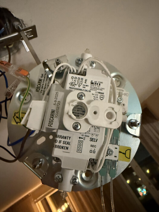 Drivdon med DALI-uttag och kablar monterade på en yta, med etikett och anslutningar synliga.