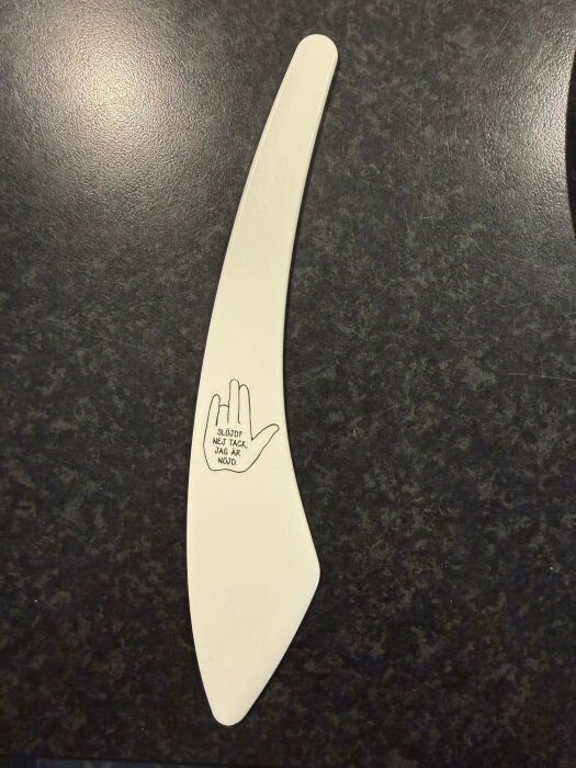 Vit plastsmörkniv med tryckt slogan och handillustration på bladet.