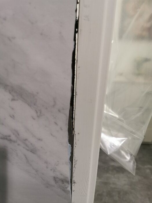 Badrumsvägg med dåligt monterad matta vid karm, visar glipor och ojämnheter, del av renoveringsprojekt.