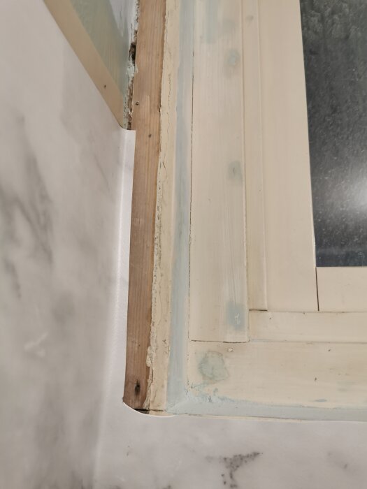 Närbild på ett fönster i ett renoverat badrum, där plastmattan inte ordentligt täcker fönsterkarmen.