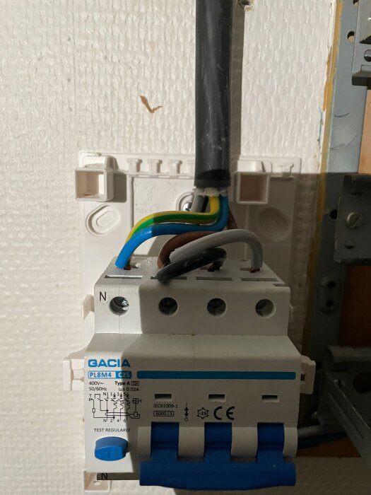 Bild av en elcentral med kopplingskablar och en Gacia brytare, där en lös skruv sitter i fasskenan.