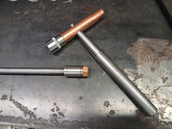 Dragstångsnyckel/hammare av metall och koppar på ett arbetsskrivbord, tillverkad för en tidigare reparerad dragstång.