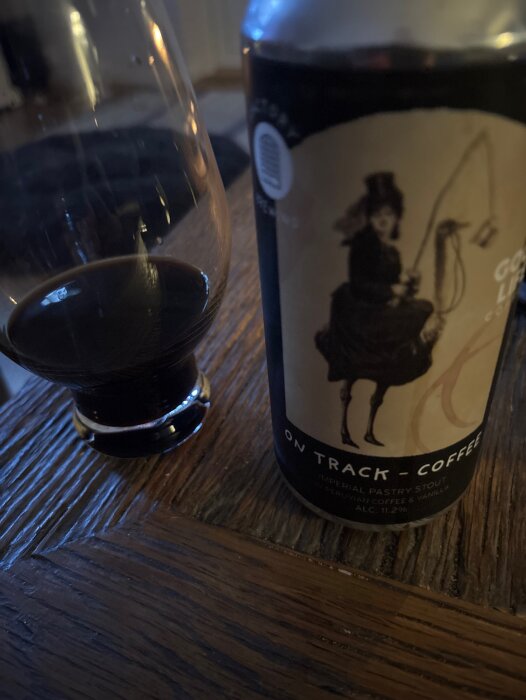 Ett glas mörkt öl bredvid en burk med etikett av en kvinna.