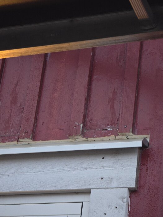 Rött träfasad med nyinstallerat vitt överbleck ovanför ett fönster, monterat av byggfirma.