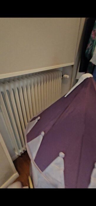 Ett element inbyggt i en vägg, med en lila tygstruktur framför, delvis skymd.