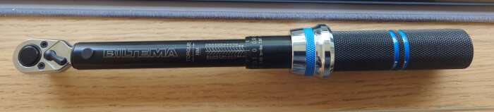 Momentnyckel från Biltema med mätmarkeringar i Newtonmeter, placerad på ett träbord.