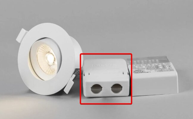 Kopplingsbox med dragavlastning för flexrör bredvid en vit downlight.