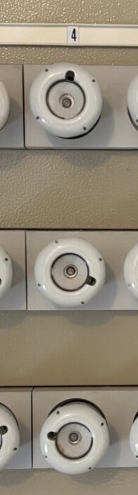 Gamla porslinssäkringar på en elcentral med ett nummer "4" ovanför, där en säkring verkar ha löst ut.