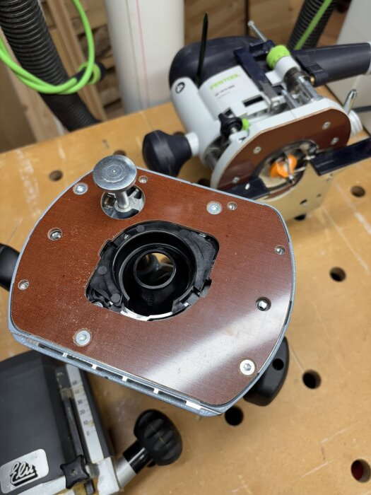 Två mellanfräsar, en Festool med tillbehör och en äldre Elu 600W, på ett arbetsbord med dammsugarslang och verktygshållare.