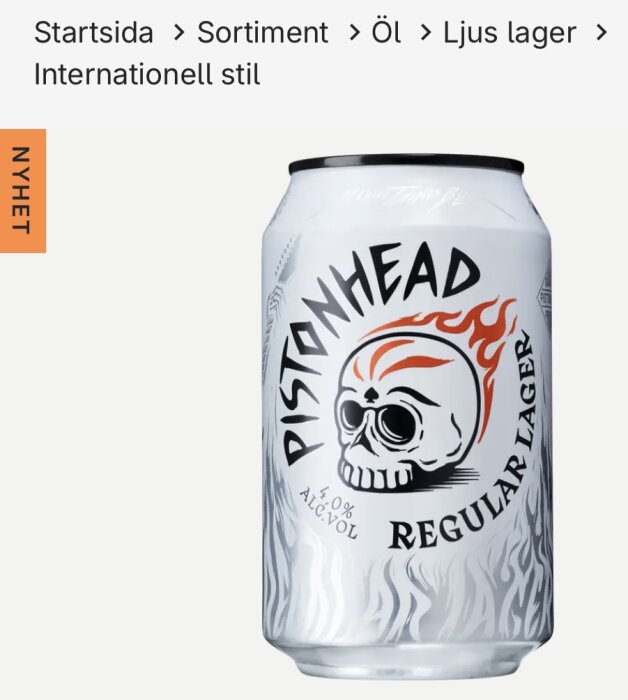 Burk med Pistonhead Regular Lager, 4,0% alkohol, med en design av en dödskalle och eldflammor på en vit bakgrund.