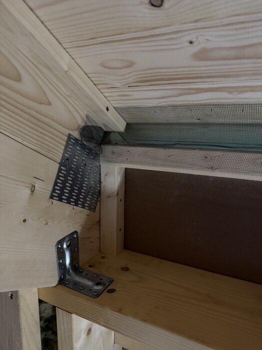 Byggkonstruktion med träreglar, luftspalt och masonitskiva; metalldetaljer synliga.