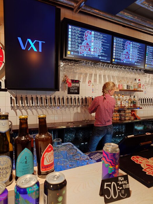 Barinteriör på Ruths med diverse ölsorter och en person i rutig skjorta som står vid dryckeskranar.