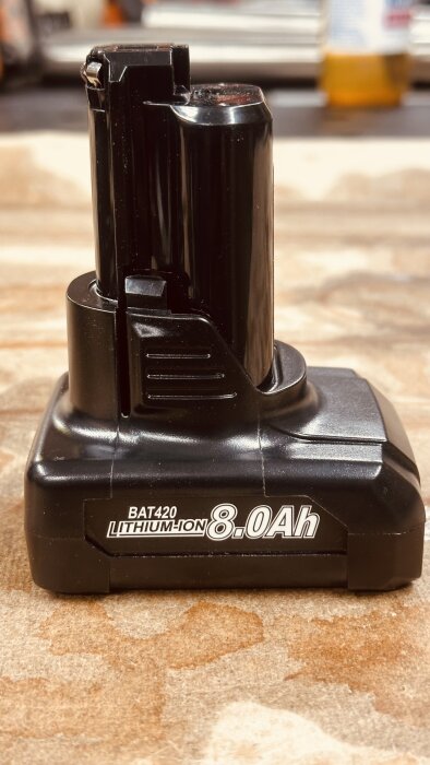 Svart Bosch 12v batteri med etikett "8.0Ah Lithium-Ion" på träyta, del av diskussion om batteriköp och prestanda.