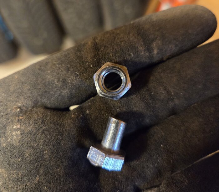 Muttrar och skadade skruvar från Biltema i en handske.