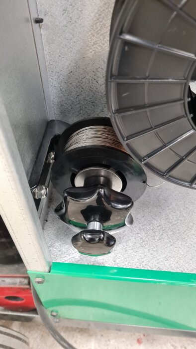 Fäste för rostfri svetstråd med två svetsrullar och en stjärnvredsmutter, del av komplett svetsinstallation.