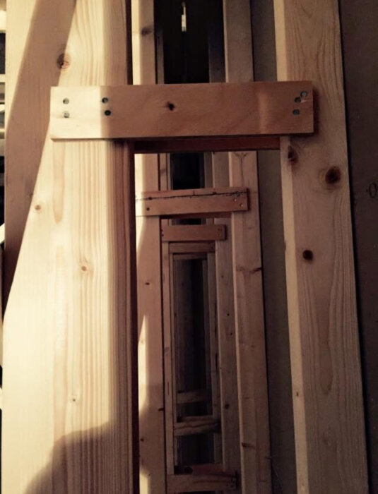 Trästomme för yttervägg med reglar och förstärkningar, potentiellt för att undvika köldbryggor.