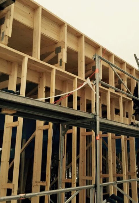 Byggarbetsplats med regelverk för villa, visar trästomme av väggar under konstruktion med ställning framför.