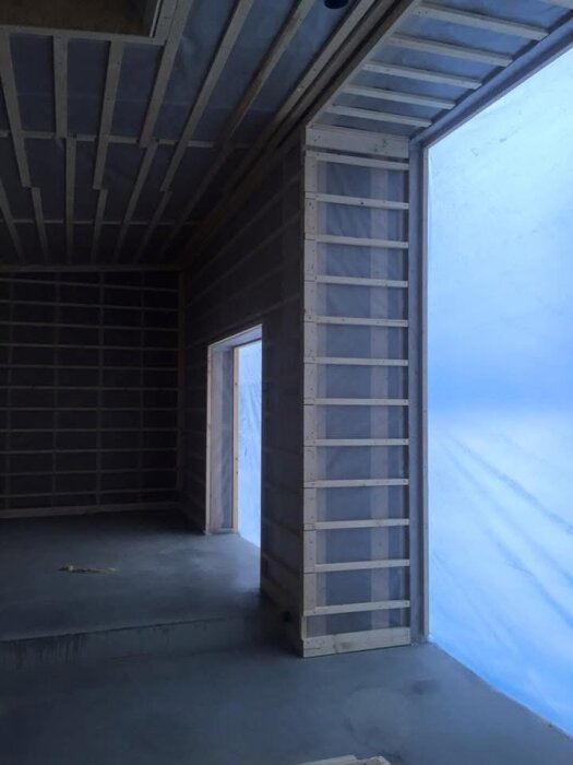 Reglade väggar och tak med plats för isolering i en nybyggd villa, plastskydd på insidan förhindrar köldbryggor.